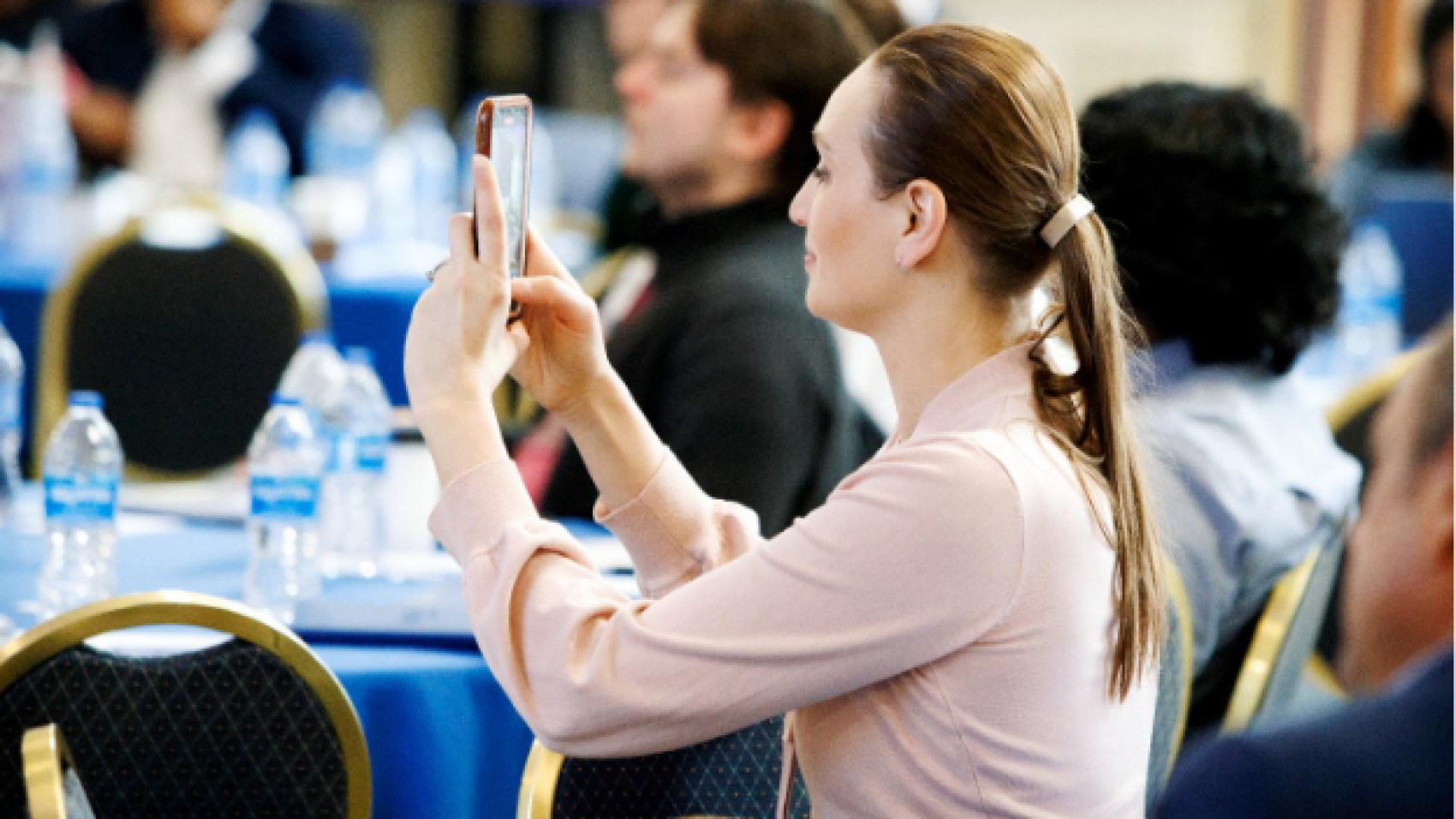A person taking a picture of her phone at networking conference