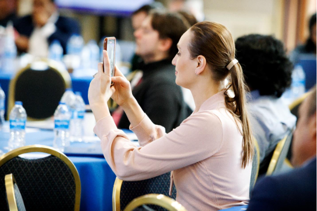 A person taking a picture of her phone at networking conference